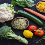 Flat lay of cauliflower, broccoli, spinach, beans, carrots, and corn as nutrient-dense foods