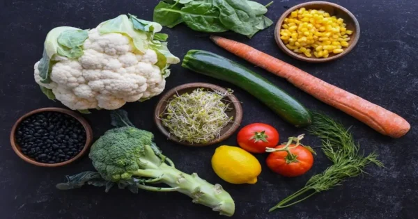 Flat lay of cauliflower, broccoli, spinach, beans, carrots, and corn as nutrient-dense foods
