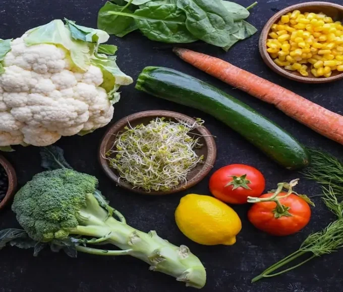 Flat lay of cauliflower, broccoli, spinach, beans, carrots, and corn as nutrient-dense foods