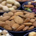 Small bowls of almonds, pecans, and pumpkin seeds showing energy-dense foods