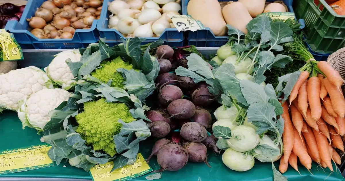 Vegetables including carrots broccoli cauliflower beets and leafy greens in market display