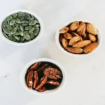 Healthy nuts and seeds including almonds, pecans, and pumpkin seeds in bowls